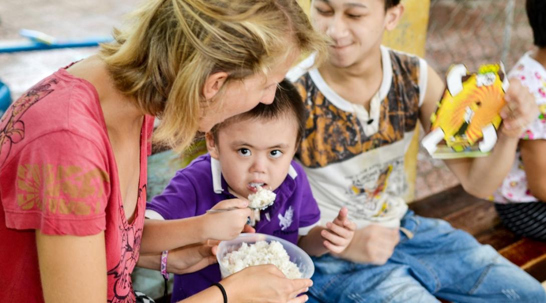 チャイルドケアボランティアがベトナムで昼食をとる子供をサポート ベトナムで昼ご飯を食べる子供たちを補助するチャイルドケアボランティア